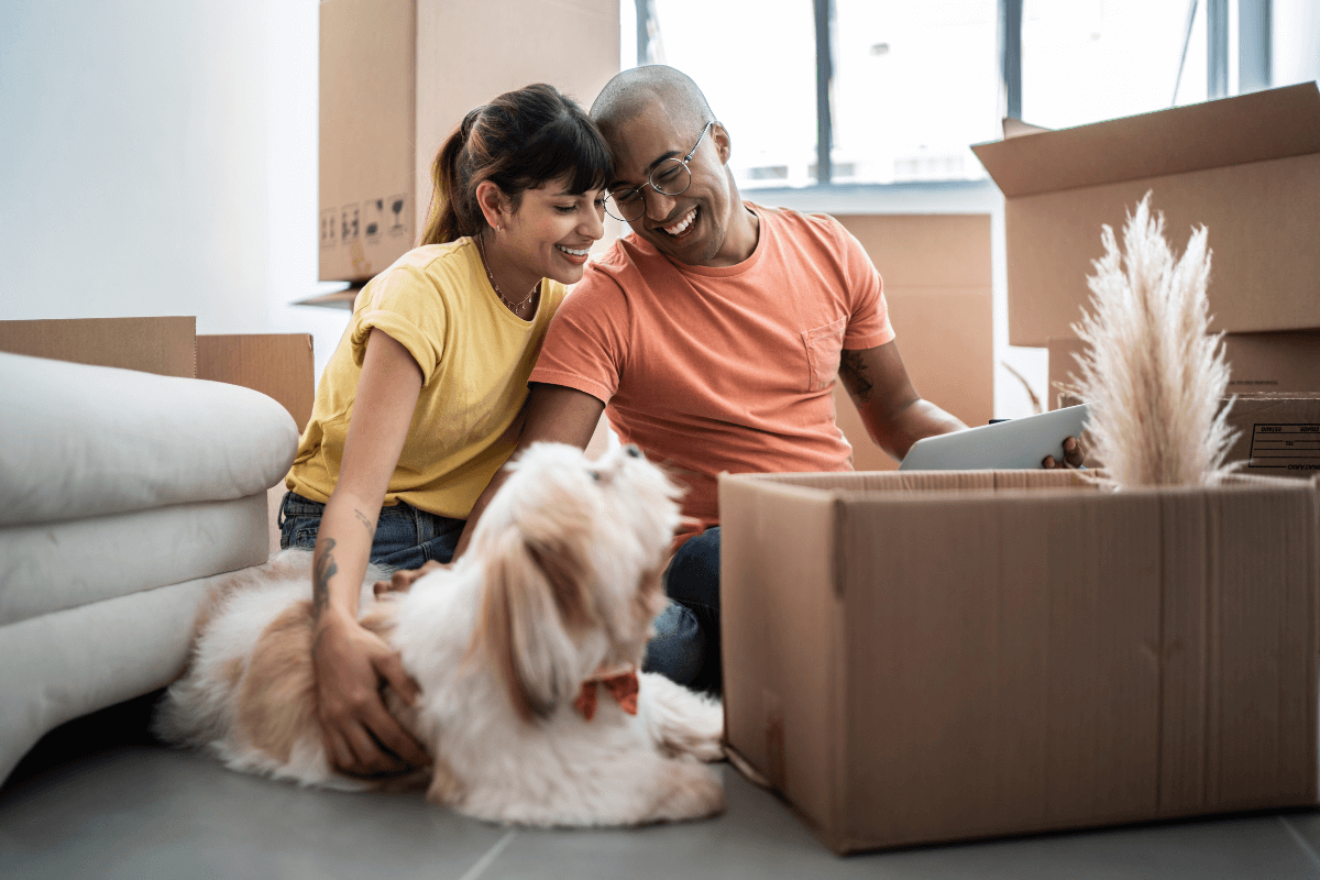A couple and their dog surrounded by boxes at home after a recent move.