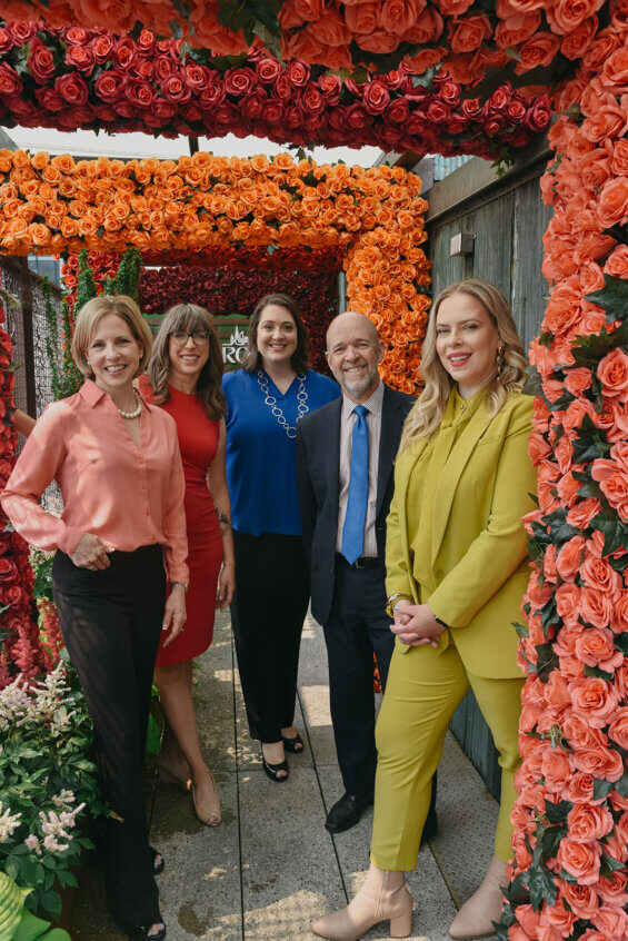 DCIs partner team stand, framed by flowers for a group shot