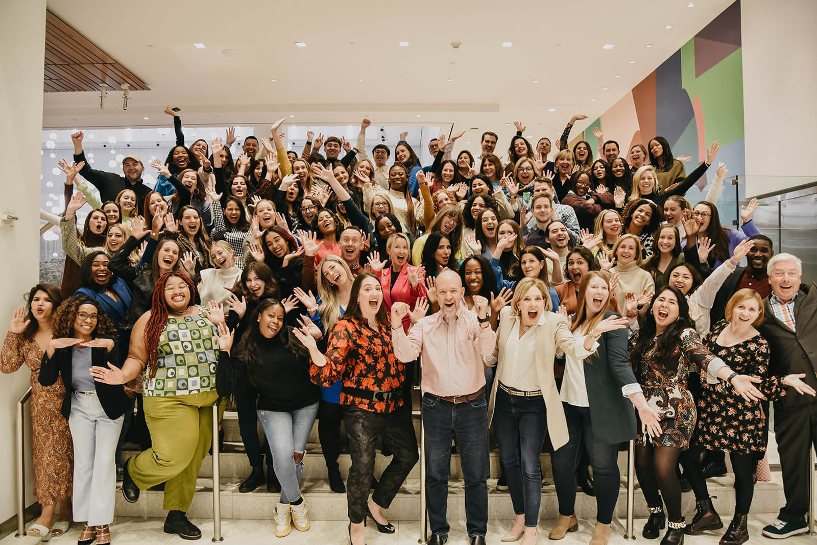 DCI's 90-person staff pose with their arms in the air and big smiles across their faces at the January retreat.