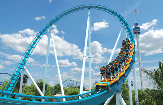Teal and orange roller coaster car coming out of the loop of a blue roller coaster track on a cloudy day