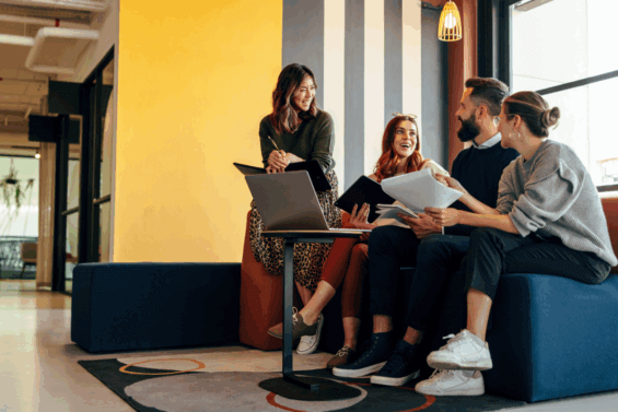 Group of four young professionals talking on a couch in an office