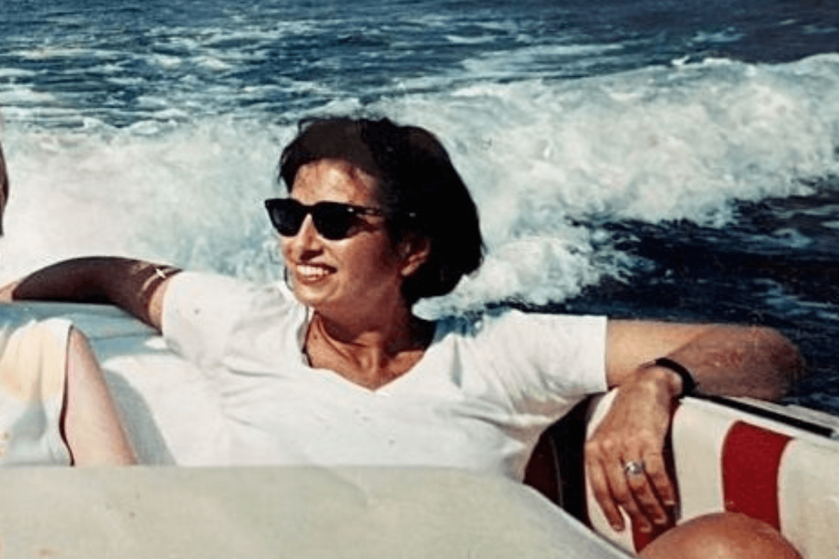 Brunette woman wearing sunglasses on a boat looking and smiling off into the distance