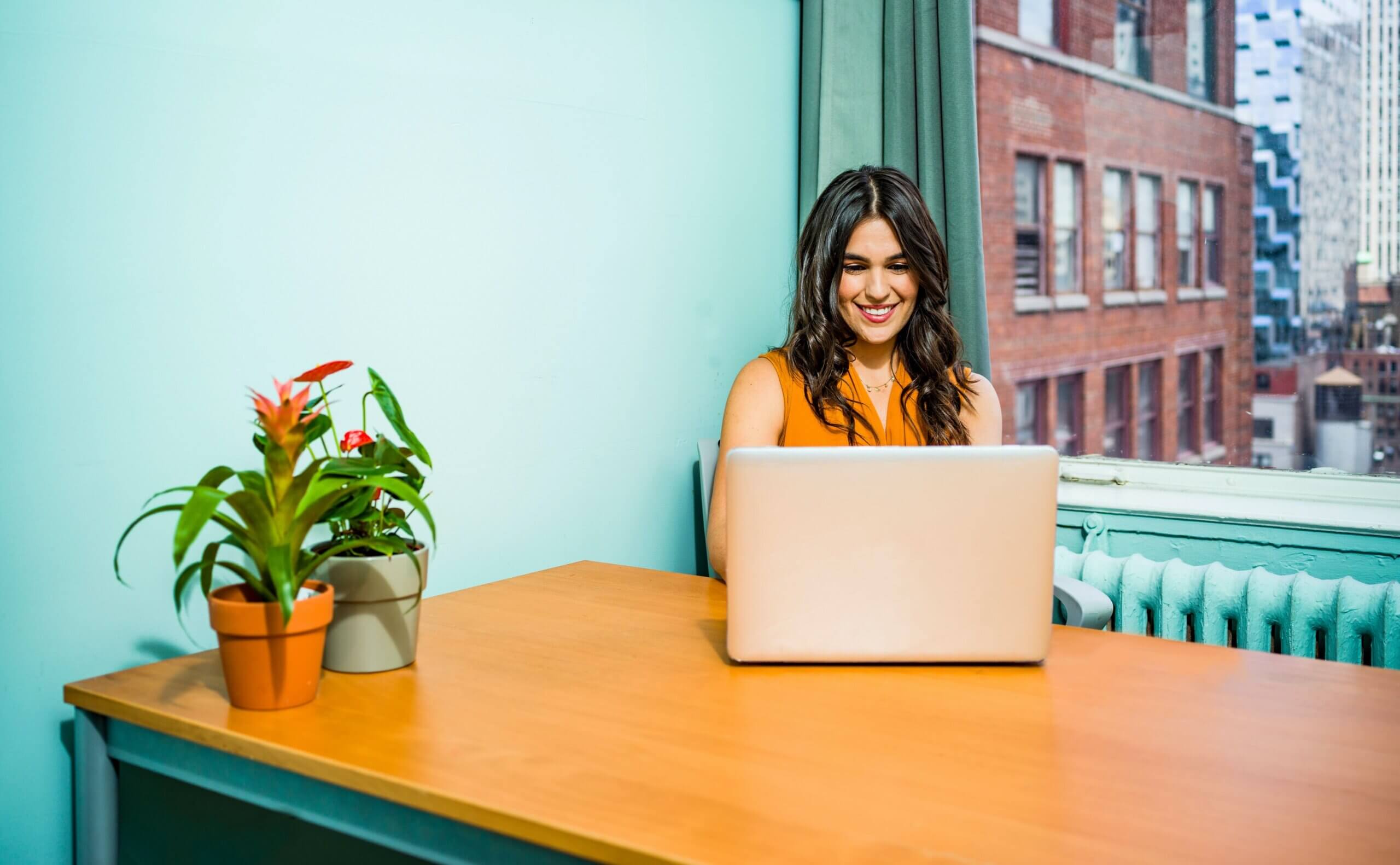 Woman smiling using laptop in colorful office space.
