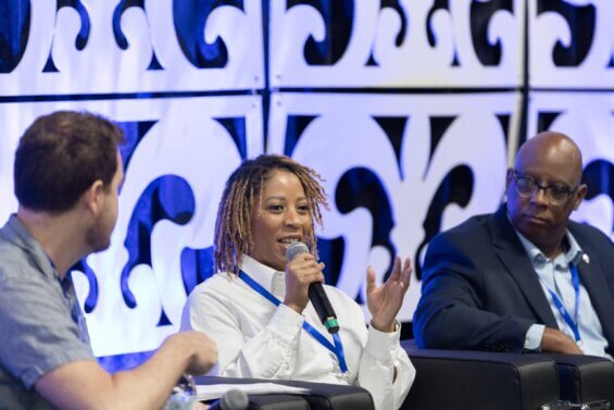 Black women in white shirt speaking into a microphone at a conference
