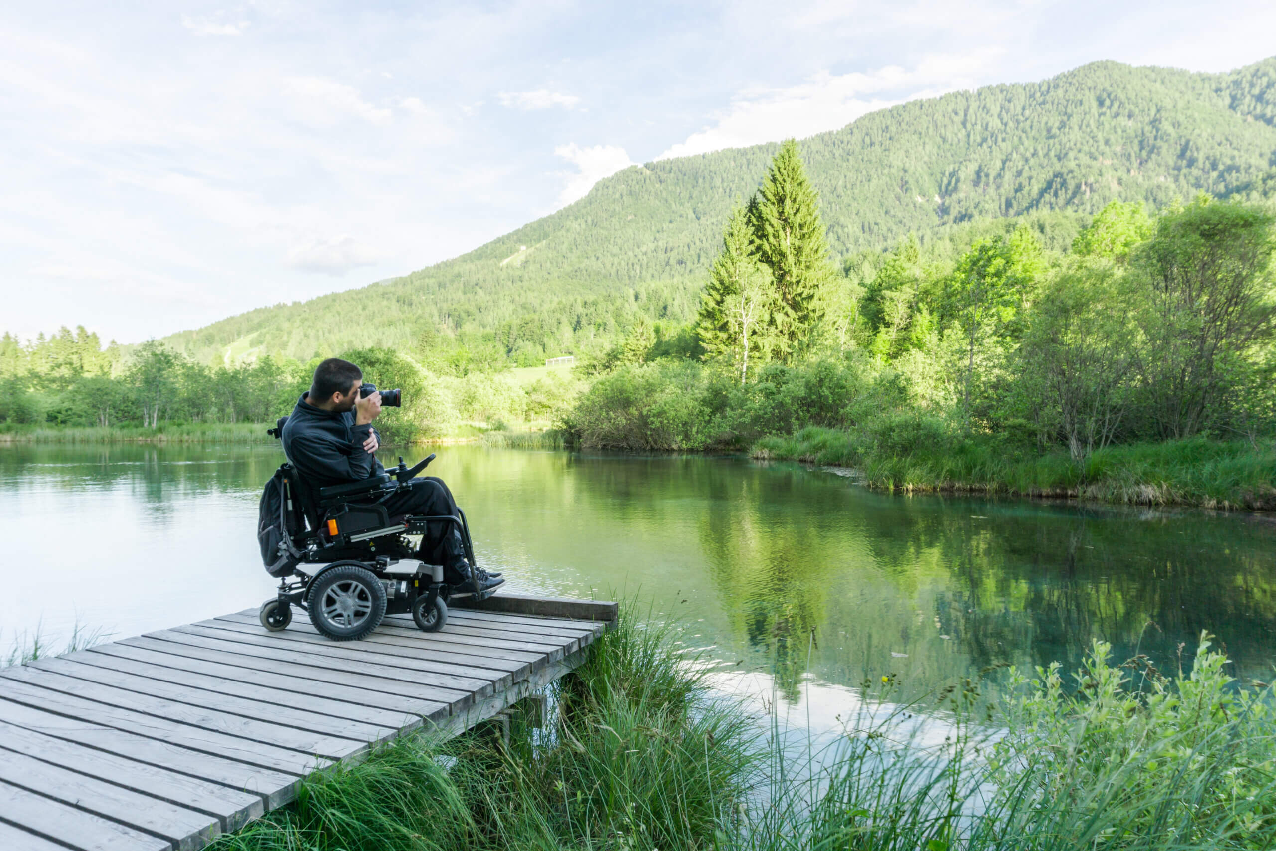 Smiling man using a mirrorless camera and traveling with a disability