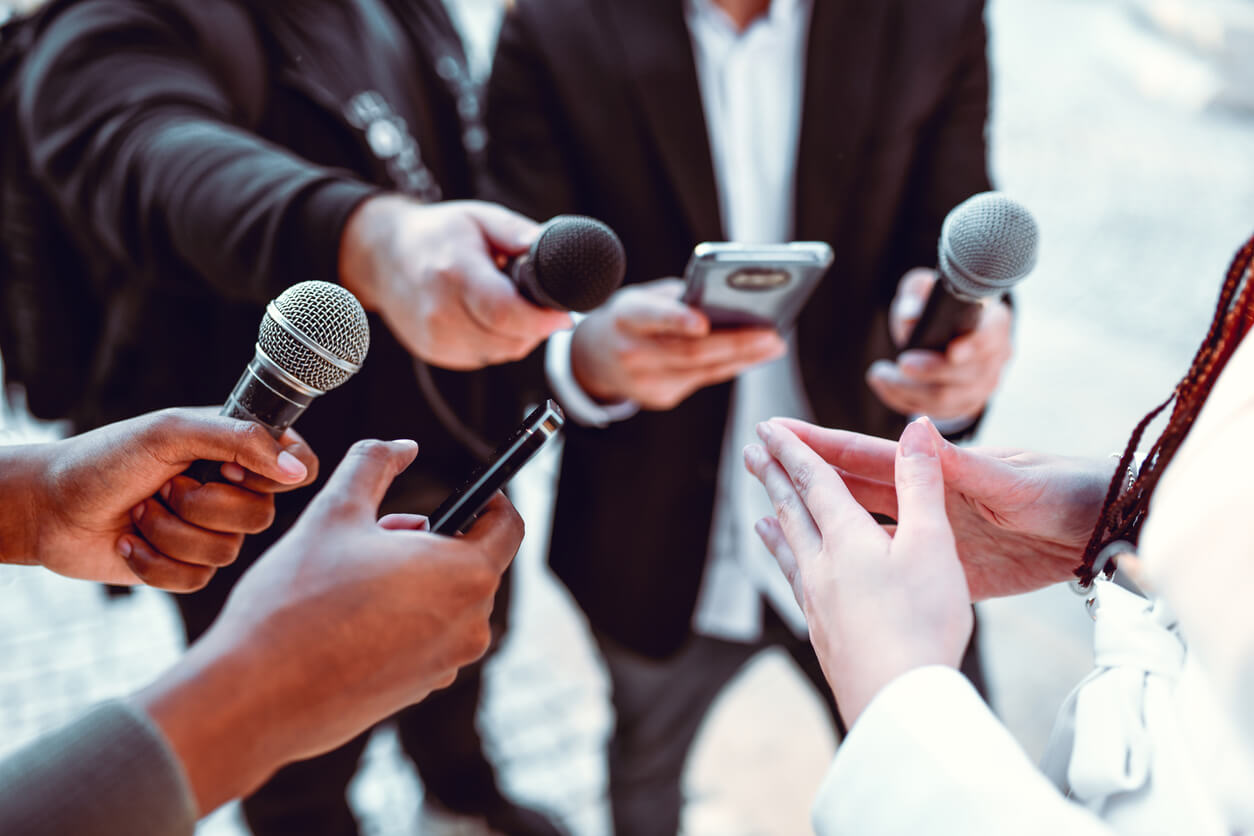 Woman utilizing national earned media and speaking to a group of attentive reporters