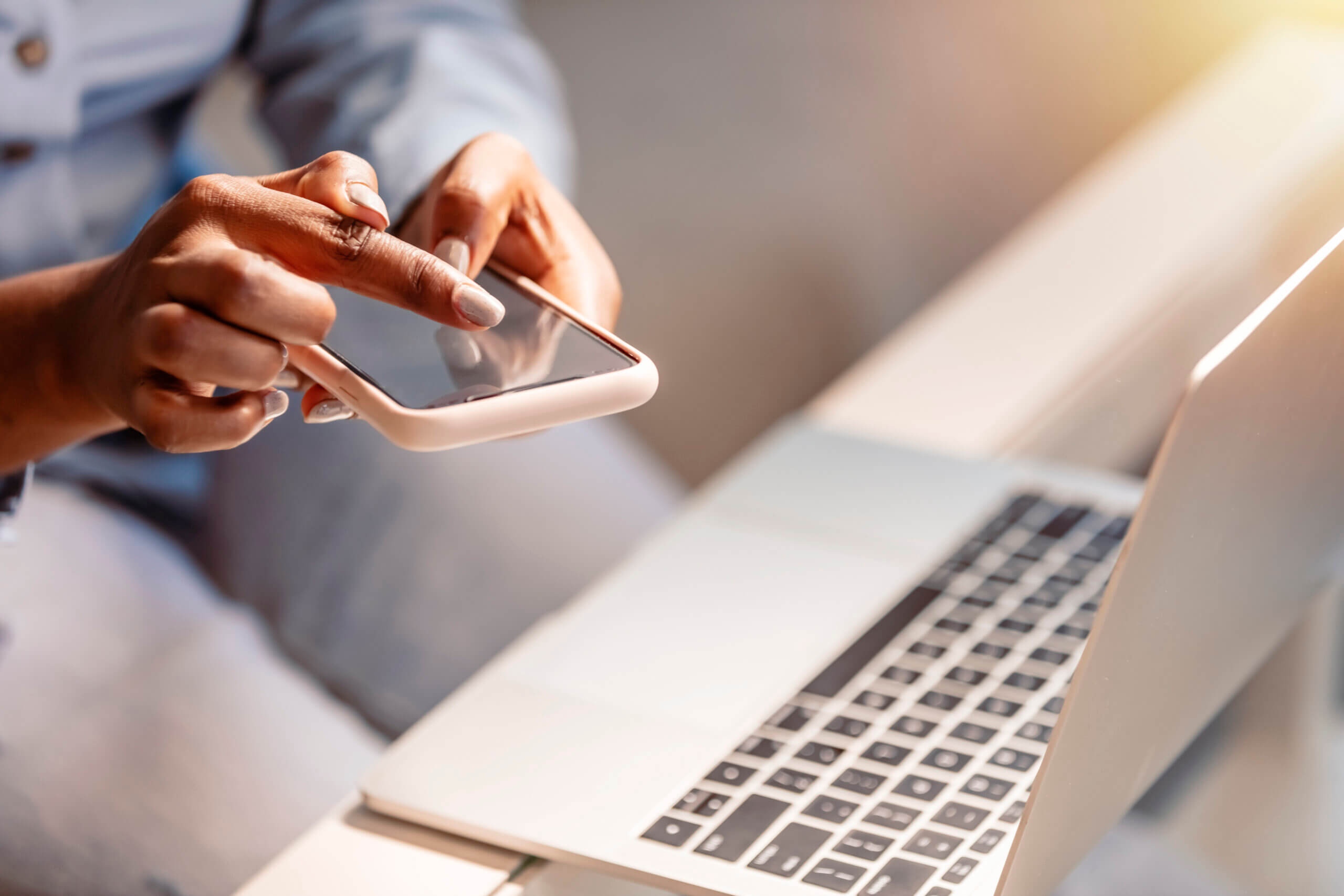 Close up on a young woman using smartphone and laptop at the office table