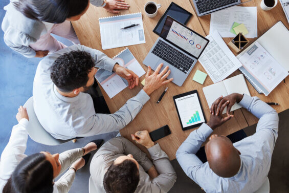Group of people sitting at a table with paper all over it rethinking a PR budget