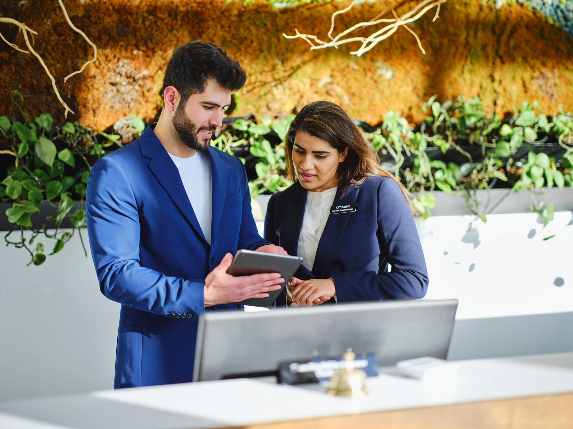Hotel staff identifying hotel sustainability initiatives that are newsworthy on a tablet at the front desk