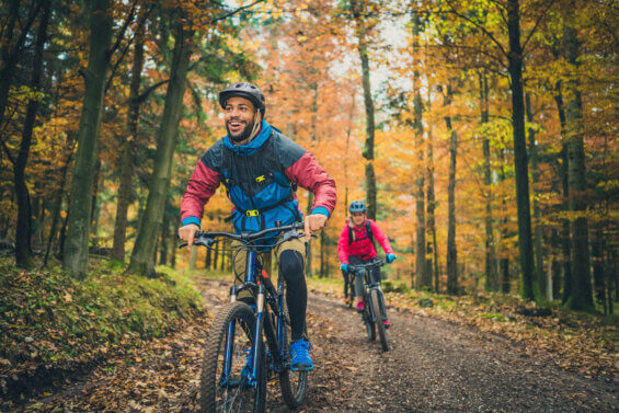 Two bikers riding through fall foliage
