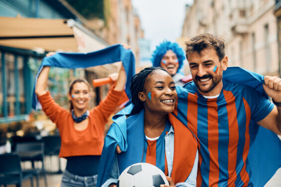 Happy couple of sports tourism fans having fun while going on soccer match with group of friends during the world cup.