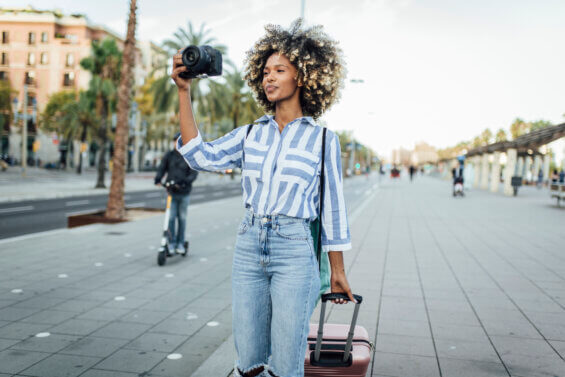 Black female tourist take a photo with her suitcase, elevating black voices in tourism marketing