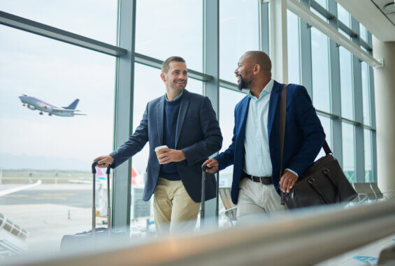 Two men walking with suitcases at an airport