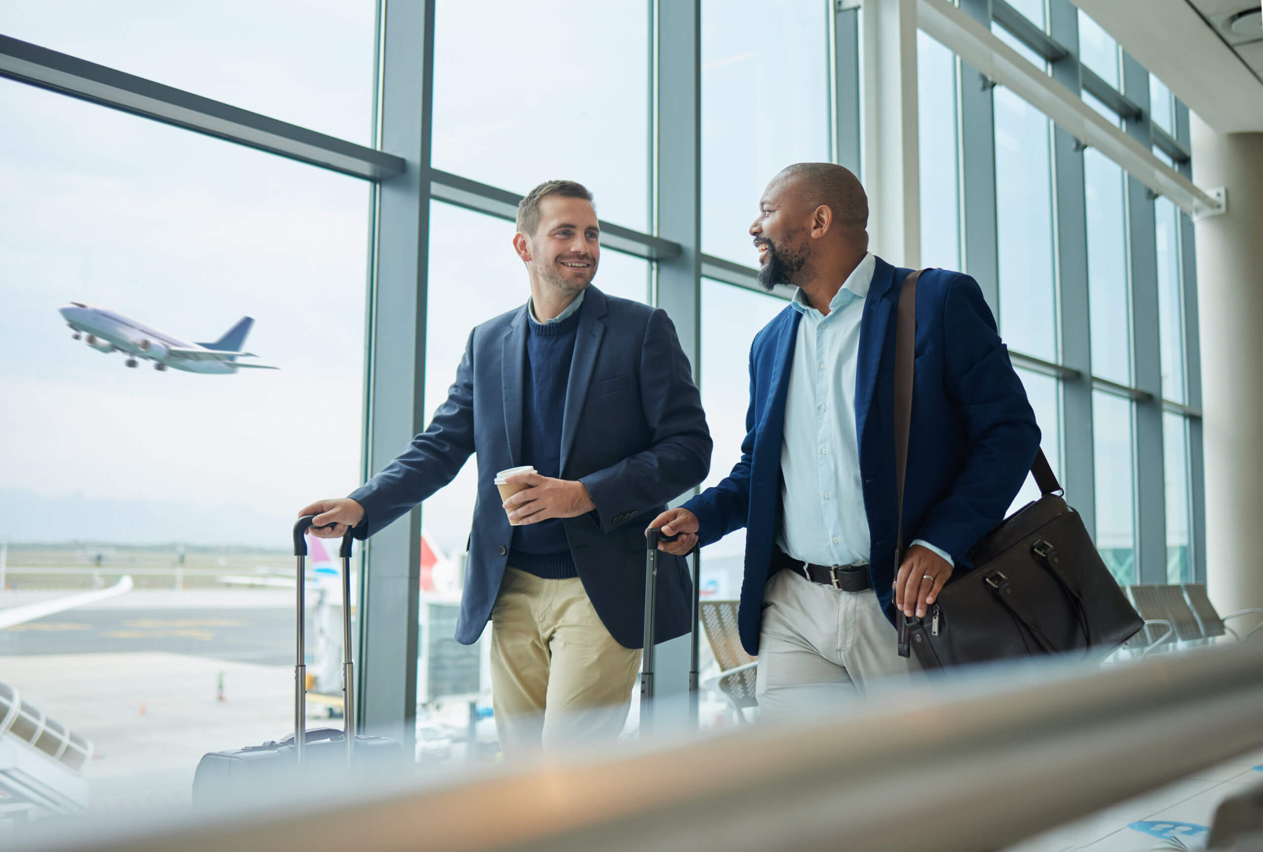 Two men walking with suitcases at an airport