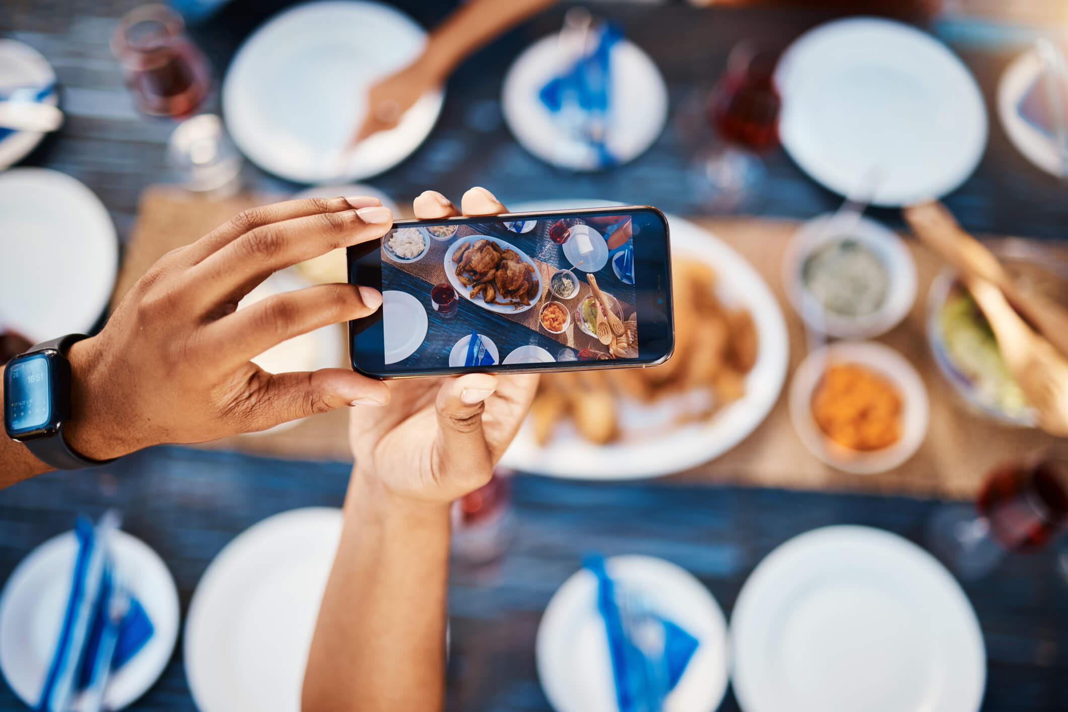 Culinary influencer taking pictures of a large meal set out on a table