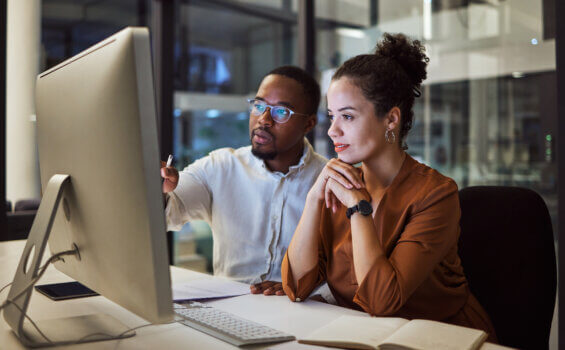 A man and a woman looking at a computer in a modern office