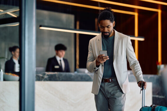 African American man texting on cell phone while checking out at the hotel.
