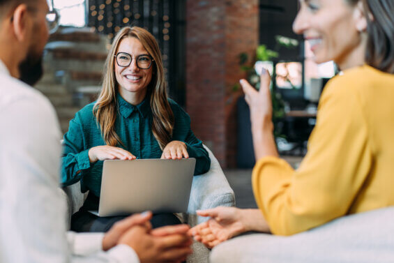 Woman who works in public relations discussing the news cycle and forming a strategy with two clients in an office.