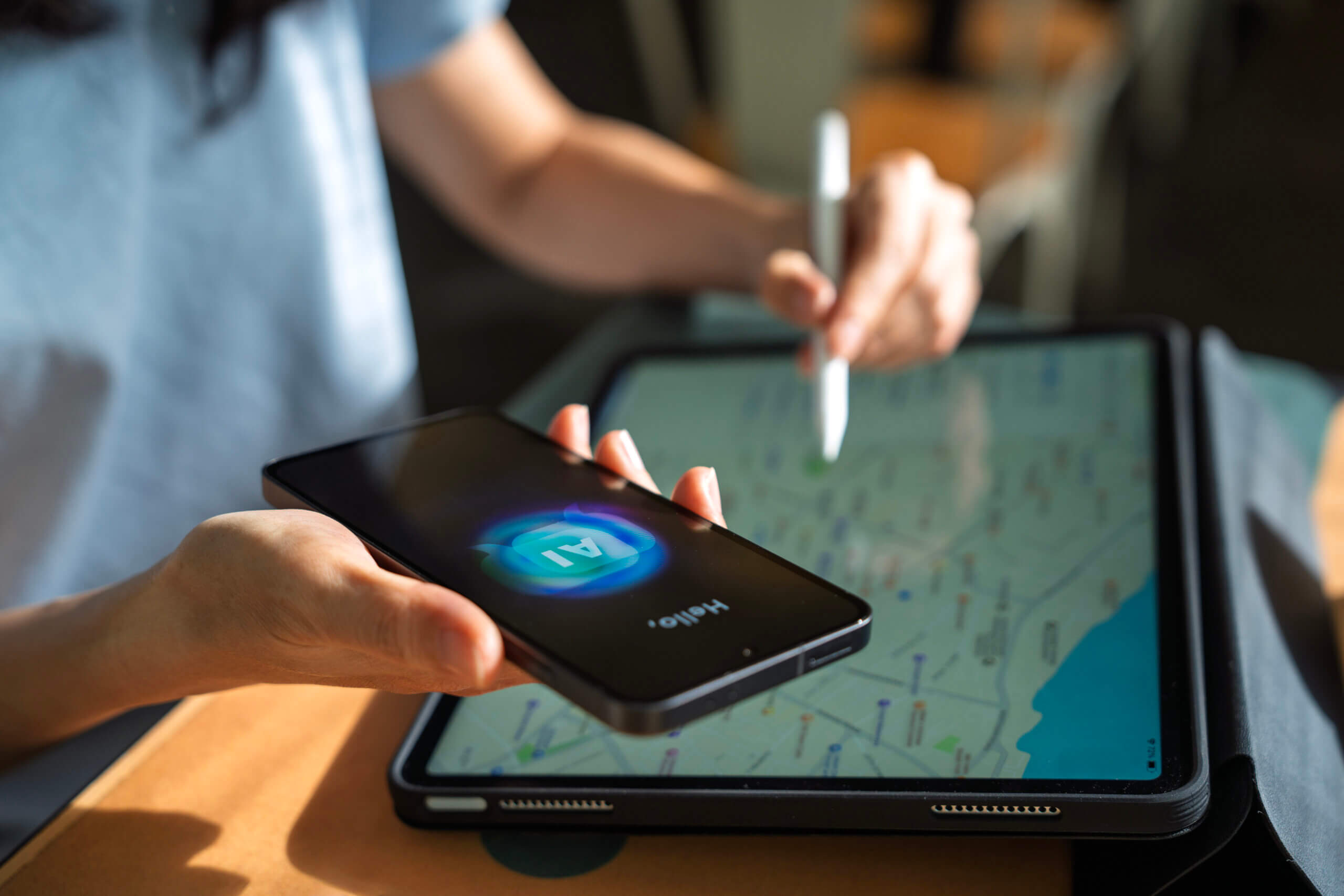 Hand holding a phone with an AI chatbox open and looking at a map on an iPad