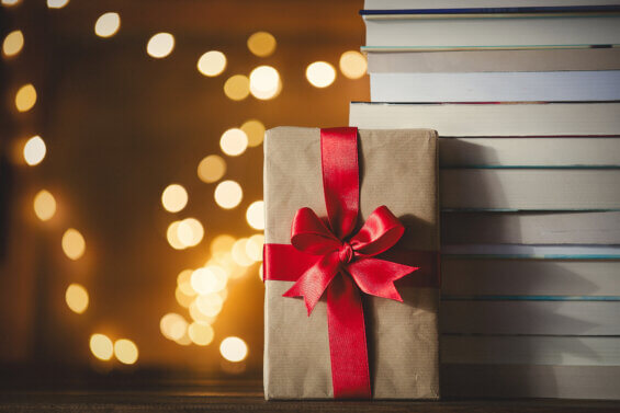 Christmas gift box and pile of books with fairy lights on background