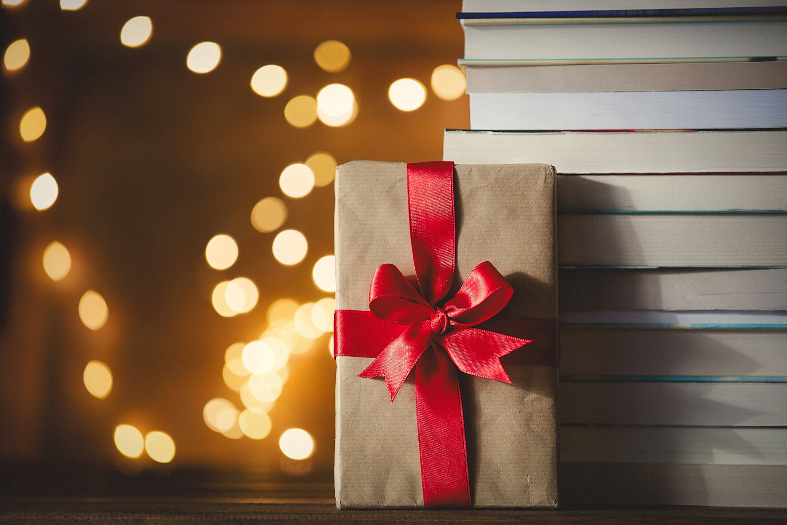 Christmas gift box and pile of books with fairy lights on background
